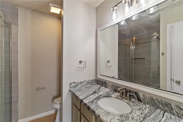 a bathroom with a granite countertop sink a mirror and a shower