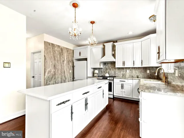 a kitchen with kitchen island granite countertop a sink cabinets and wooden floor