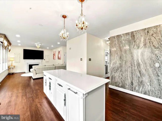 a large white kitchen with a large window a island and stainless steel appliances