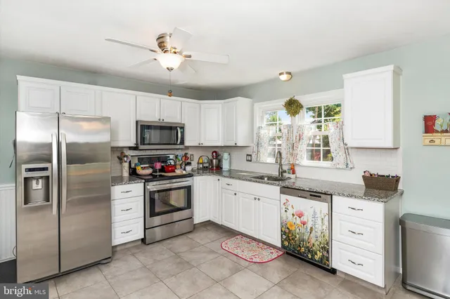 a kitchen with granite countertop a sink stainless steel appliances and white cabinets