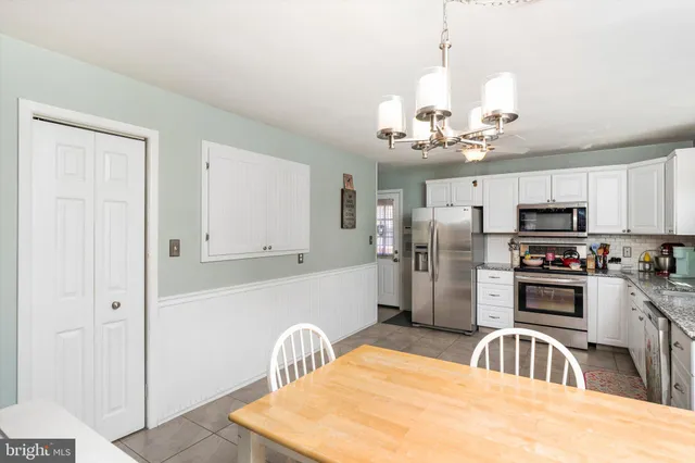 a kitchen with stainless steel appliances kitchen island granite countertop a refrigerator a sink dishwasher a oven with white cabinets and wooden floor