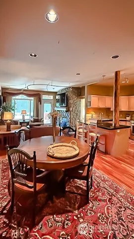 a view of a living room and kitchen with stainless steel appliances wooden floor and large windows