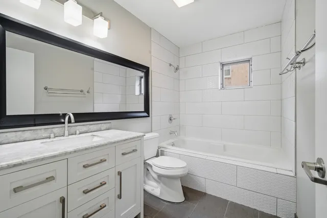 a bathroom with a granite countertop sink toilet mirror and bathtub