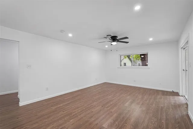 a view of an empty room with a window and wooden floor