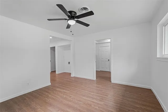 an empty room with wooden floor and ceiling fan