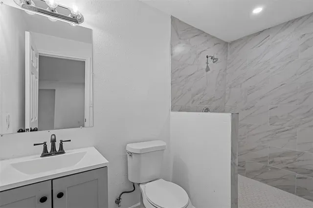 a bathroom with a toilet sink vanity and mirror