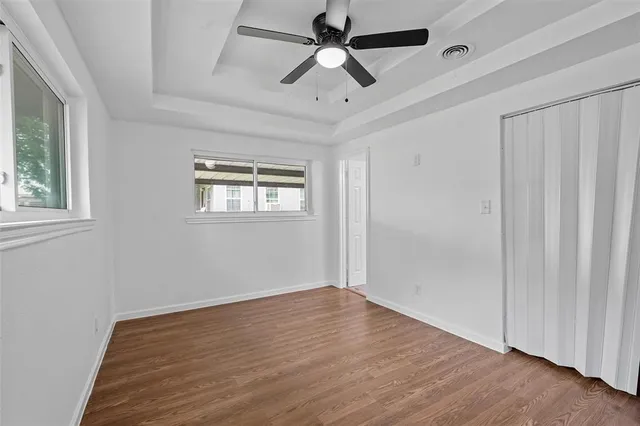 a view of empty room with wooden floor and fan