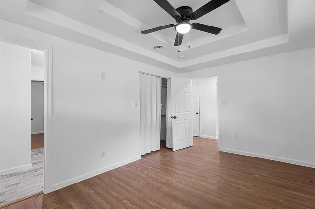 an empty room with wooden floor and ceiling fan