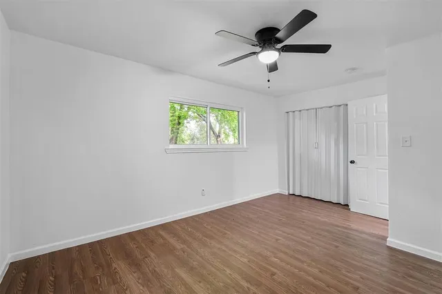 a view of empty room with wooden floor and ceiling fan