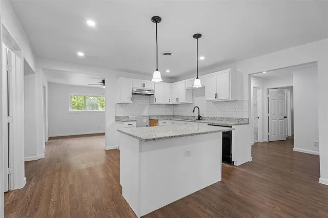 a kitchen with stove and wooden floor
