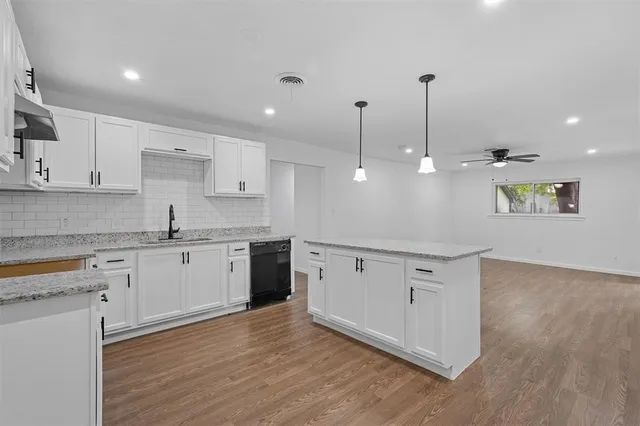 a large kitchen with granite countertop a white stove top oven and white cabinets
