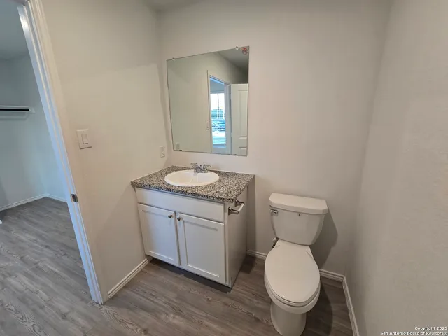 a bathroom with a granite countertop toilet a sink and a mirror