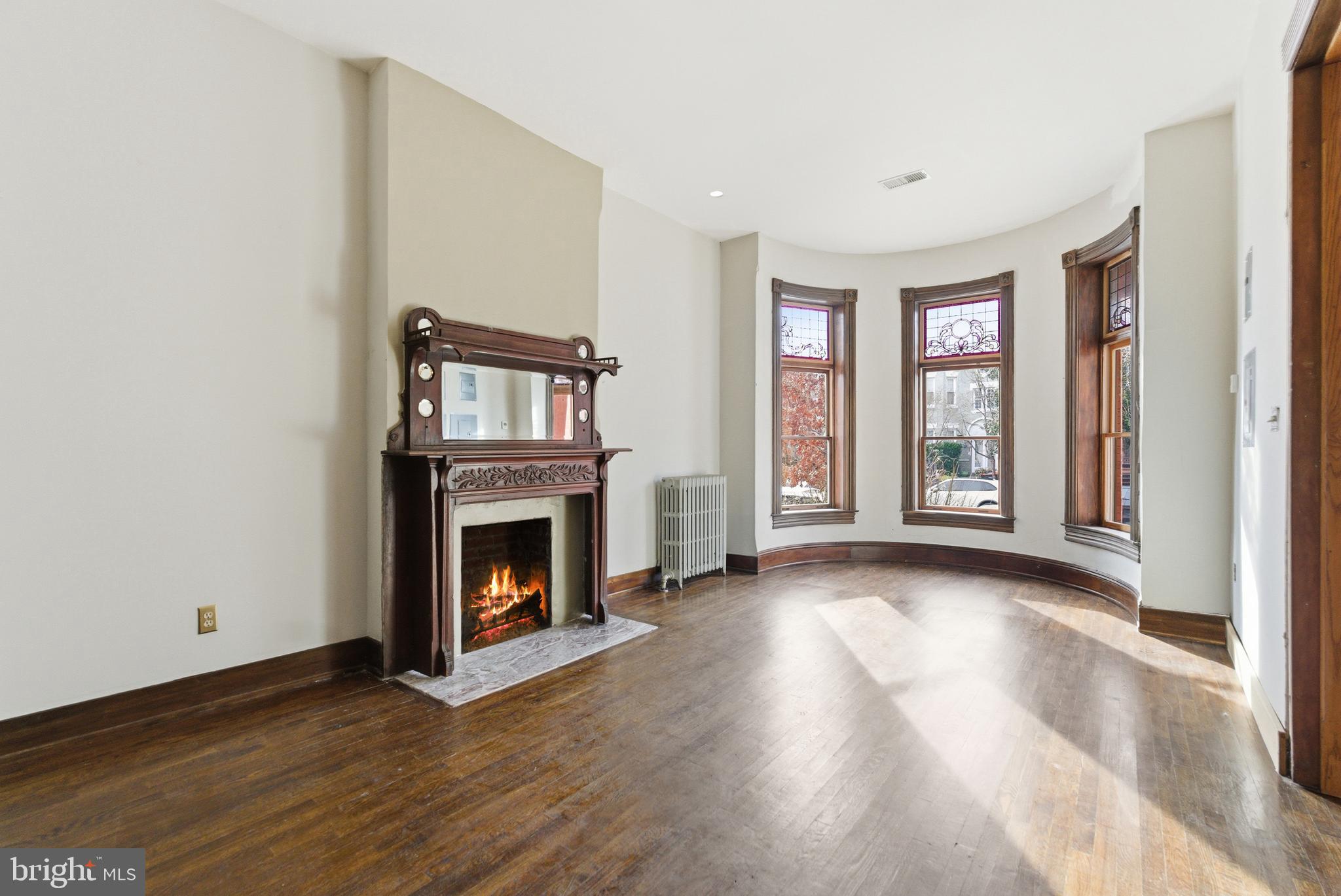 1827 13th Street Northwest Washington, DC 20009 - Photo 5 of 15 an empty room with wooden floor fireplace and windows