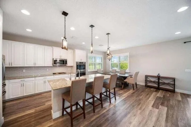 a view of a dining room and livingroom with furniture wooden floor a chandelier