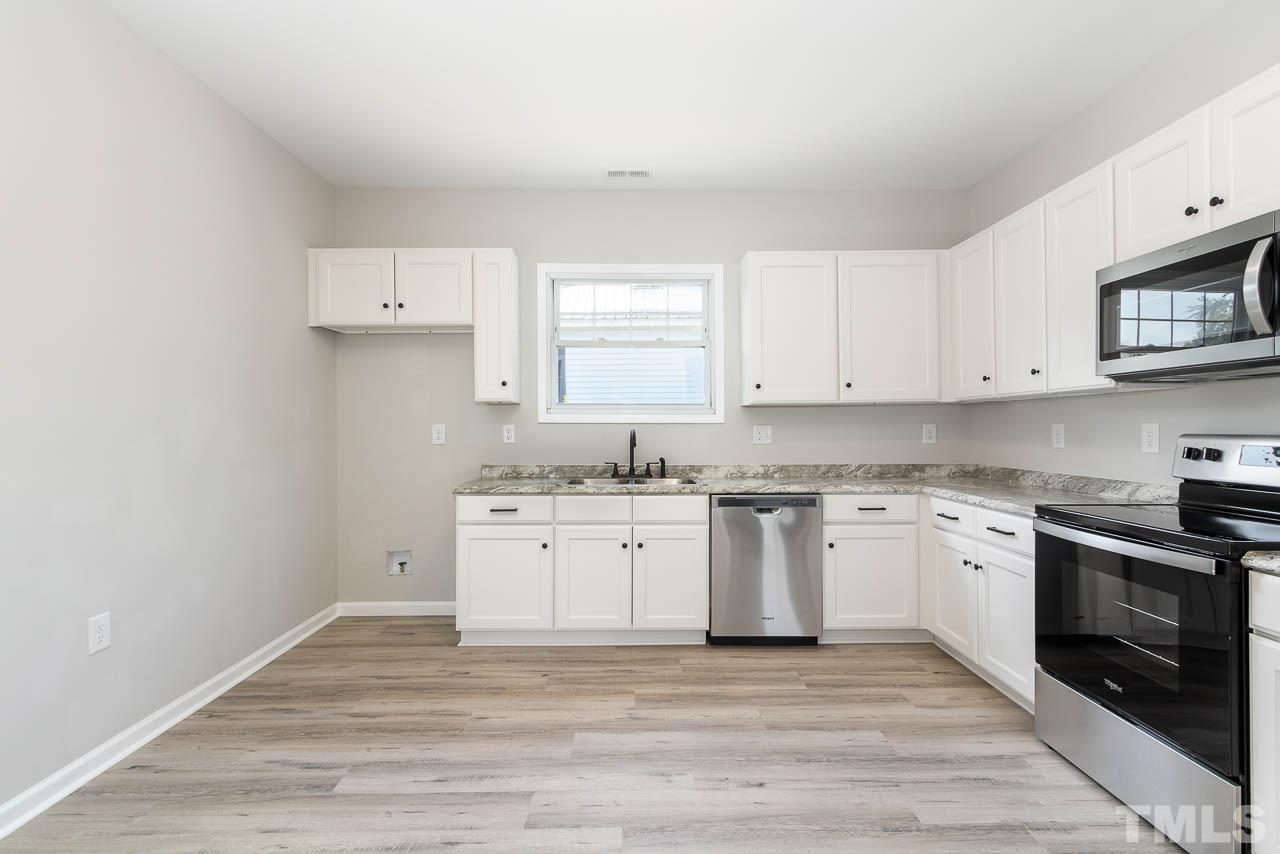 206 Edgar Street Roxboro, NC 27573 - Photo 6 of 18 a kitchen with granite countertop white cabinets stainless steel appliances a sink and a window
