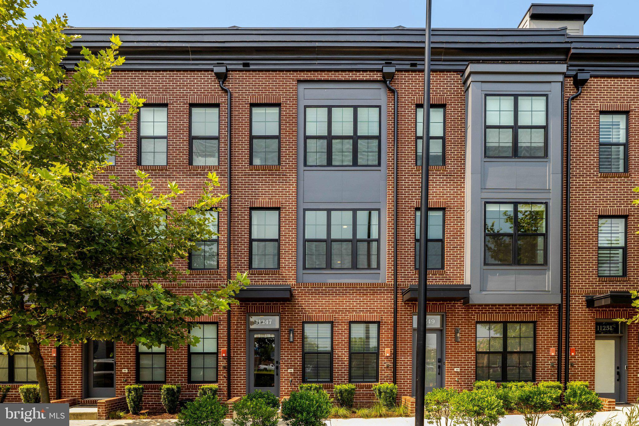 11247 Beaker Street Reston, VA 20190 - Photo 1 of 54 Modern brick townhomes with greenery.
