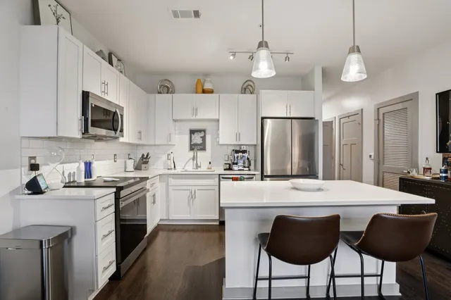 a kitchen with cabinets a center island and stainless steel appliances