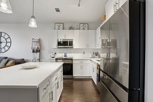 a kitchen with stainless steel appliances a sink stove refrigerator and cabinets