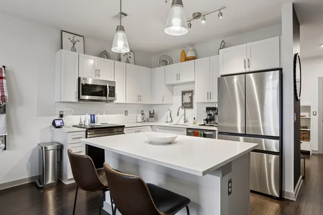 a kitchen with stainless steel appliances a stove a sink dishwasher a refrigerator white cabinets and wooden floor