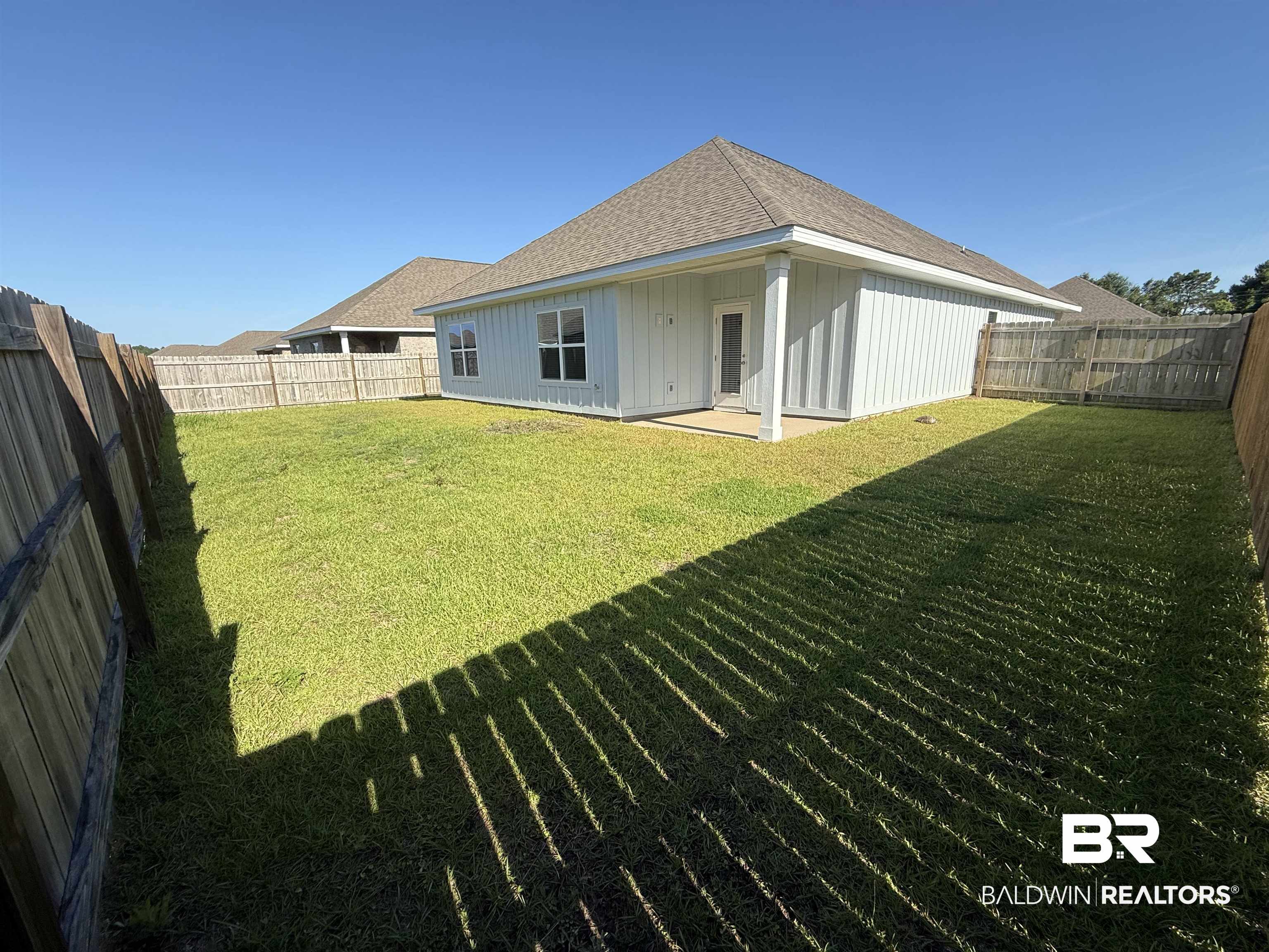 23247 Lieutenant Avenue Foley, AL 36535 - Photo 38 of 47 Spacious backyard featuring a fenced perimeter, a rear patio, and a light-colored exterior with a shingle roof