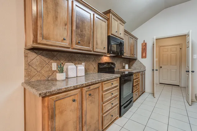 a kitchen with granite countertop a stove top oven microwave and cabinets