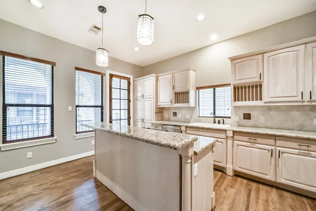 a kitchen with stainless steel appliances granite countertop stove a sink dishwasher a refrigerator and white cabinets with wooden floor