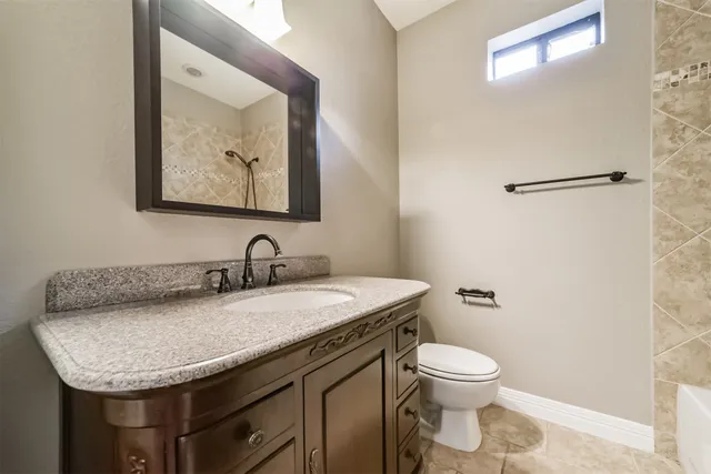 a bathroom with a granite countertop sink and a toilet
