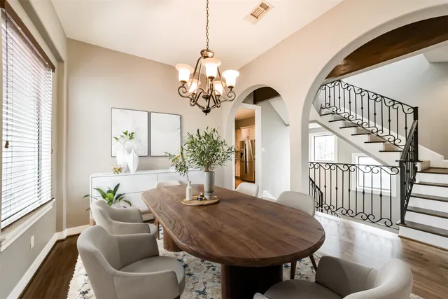 a dining room with wooden floor a chandelier a wooden table and chairs