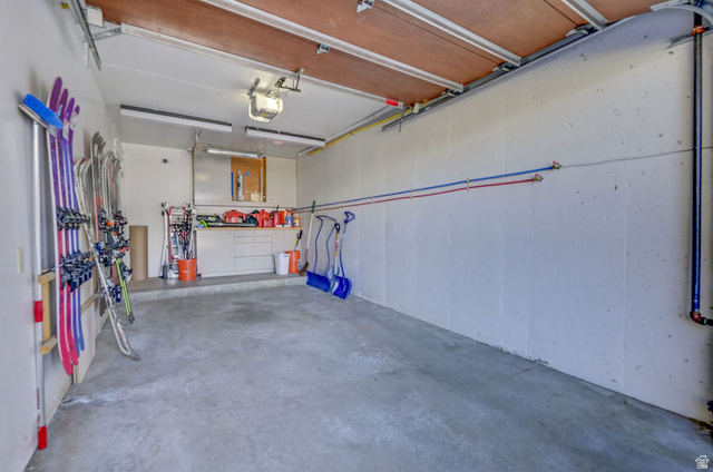 9699 Bypass Road, Unit 5 Alta, UT 84092 - Photo 46 of 54 Concrete floor garage featuring a built-in workbench with storage cabinetry, overhead fluorescent lighting, and visible utility lines