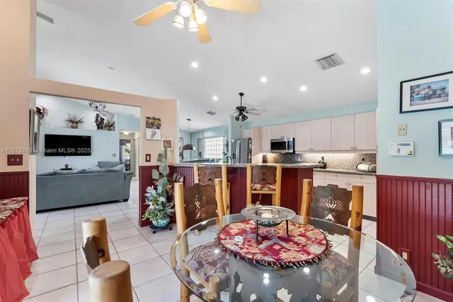 a living room with stainless steel appliances furniture a rug kitchen view and a chandelier