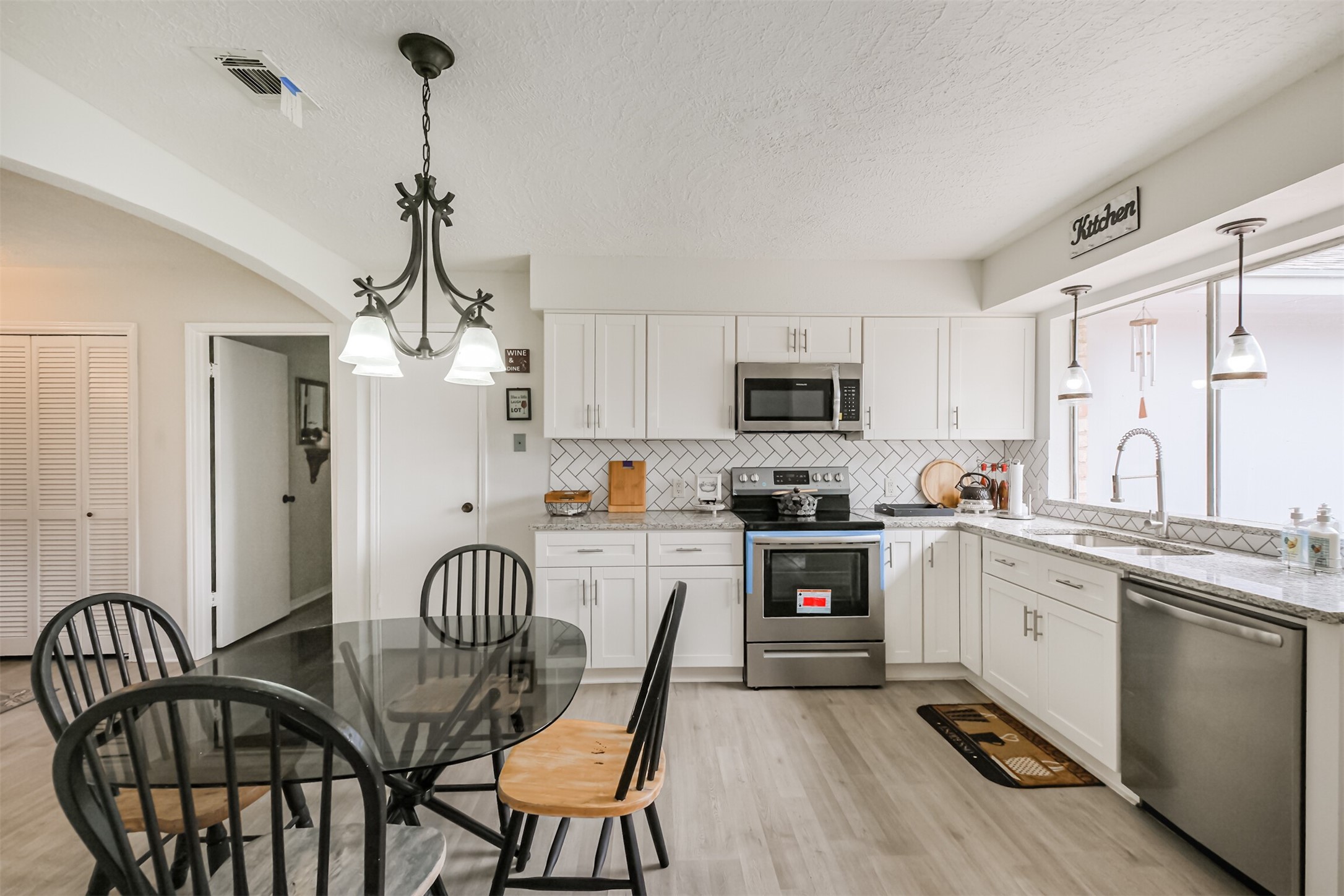 2705 Parrott Avenue Rosenberg, TX 77471 - Photo 8 of 37 a kitchen with stainless steel appliances granite countertop a stove top oven a sink dishwasher a dining table and chairs with wooden floor