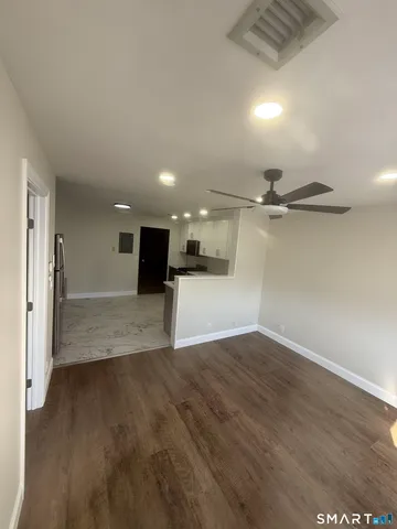 a view of a big room with wooden floor and a kitchen
