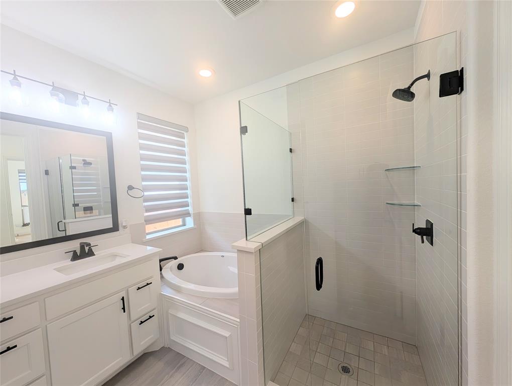15532 Fringe Tree Road Frisco, TX 75035 - Photo 10 of 31 Full bathroom featuring a frameless glass shower enclosure with matte black fixtures, a built-in soaking tub, and a white vanity with a quartz countertop