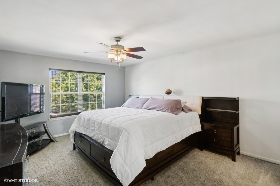 990 Oak Ridge Boulevard Elgin, IL 60120 - Photo 9 of 19 a bedroom with a bed a chandelier and a flat tv screen on the dresser