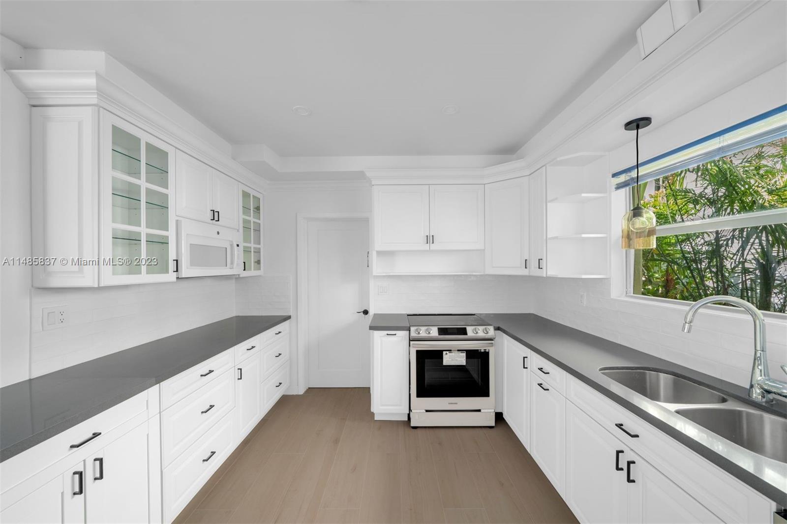 2385 North Bay Road Miami Beach, FL 33140 - Photo 14 of 35 a kitchen with granite countertop white cabinets and a stove top oven