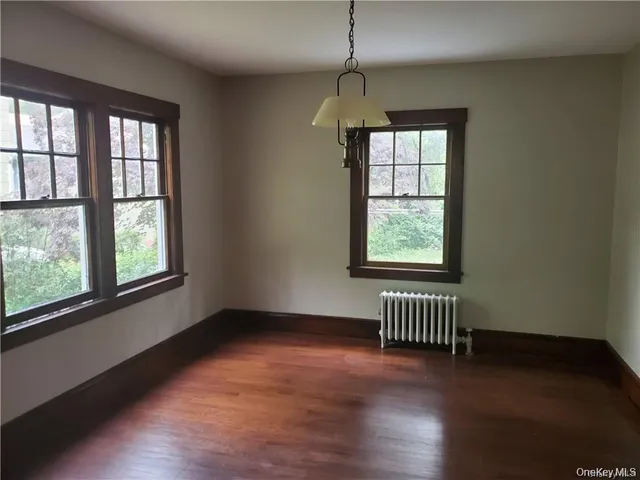an empty room with wooden floor chandelier and windows