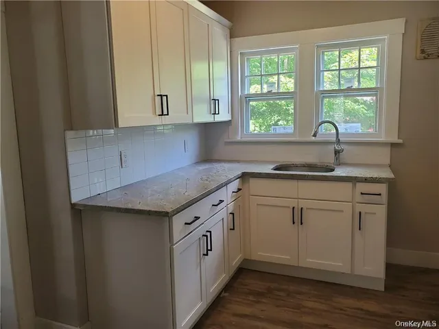 a kitchen with granite countertop white cabinets and a window