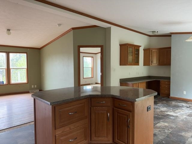 1335 Big Noise Pit Road Two Harbors, MN 55616 - Photo 9 of 20 Kitchen with crown molding, a center island, brown cabinetry, vaulted ceiling, and baseboards