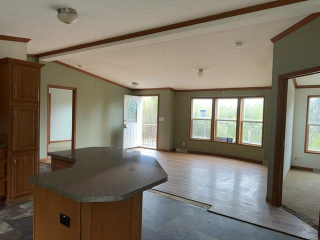 1335 Big Noise Pit Road Two Harbors, MN 55616 - Photo 19 of 20 Kitchen with ornamental molding, dark countertops, a center island, brown cabinetry, and open floor plan