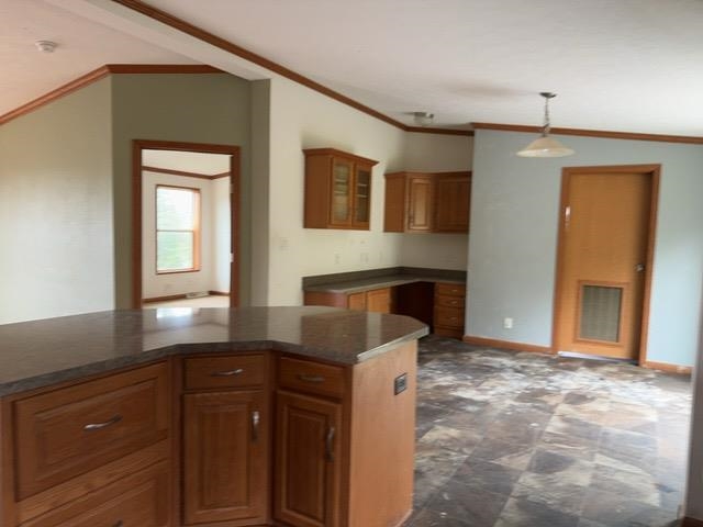 1335 Big Noise Pit Road Two Harbors, MN 55616 - Photo 8 of 20 Kitchen with dark countertops, brown cabinets, hanging light fixtures, ornamental molding, and glass insert cabinets