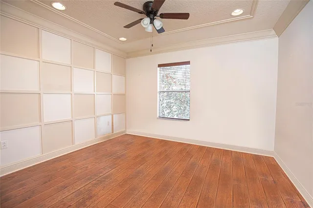 an empty room with wooden floor chandelier fan and windows