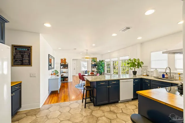 a room with stainless steel appliances kitchen island granite countertop a sink and cabinets