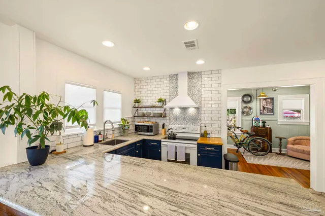 a kitchen with stainless steel appliances kitchen island granite countertop a sink counter space cabinets and a couch