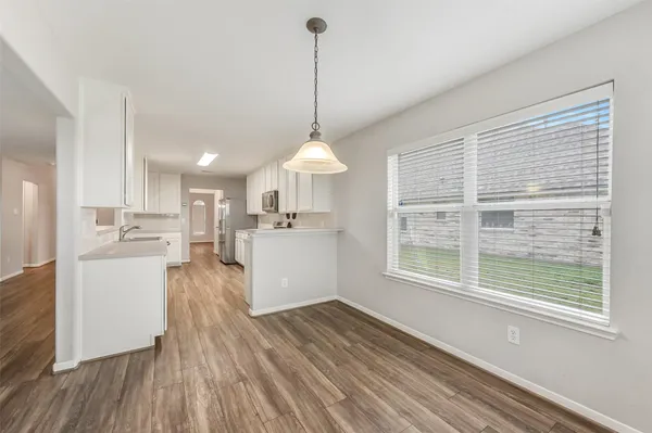 a view of a kitchen and an empty room with wooden floor kitchen view