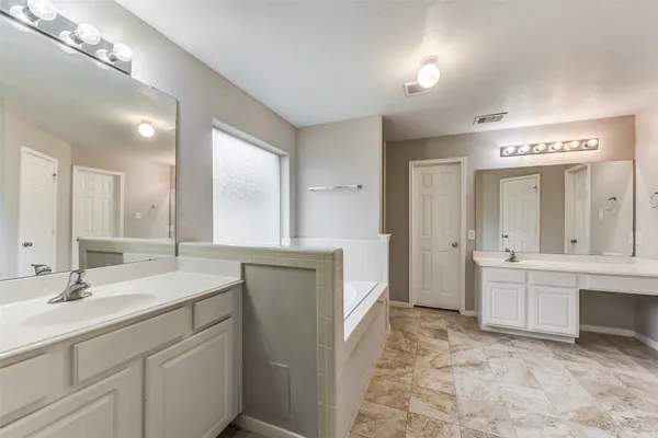 a spacious bathroom with a granite countertop sink a mirror and a bathtub