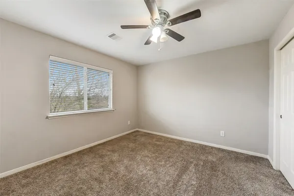 an empty room with a window and a fan