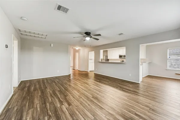 a view of an empty room with a window and wooden floor