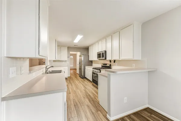 a kitchen with stainless steel appliances a sink a stove a refrigerator cabinets and a window