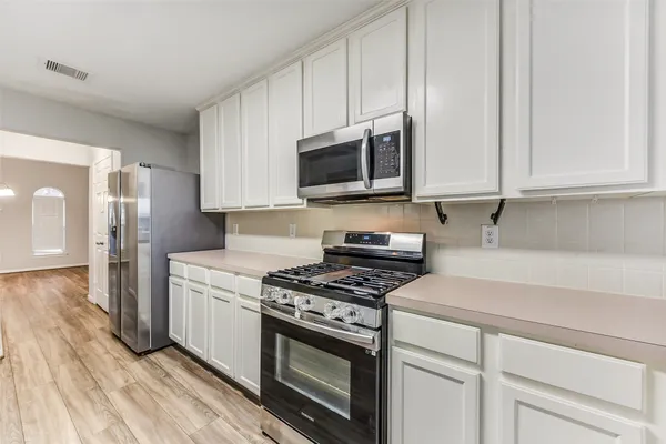 a kitchen with stainless steel appliances granite countertop a stove a microwave and a white cabinets