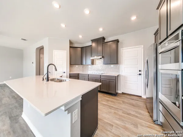 a large white kitchen with kitchen island a stove a sink a refrigerator and cabinets